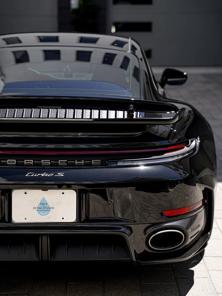 Close rear view of the Turbo S badge, light bar, raised wing and right exhaust outlet.