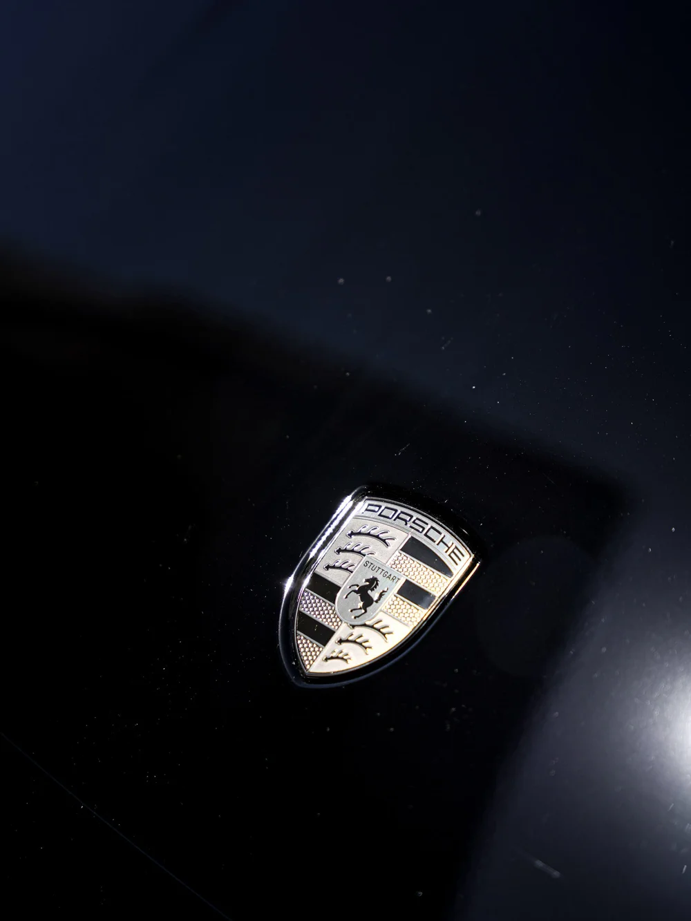 Porsche crest and reflected light on the Jet Black Metallic Turbo S hood.