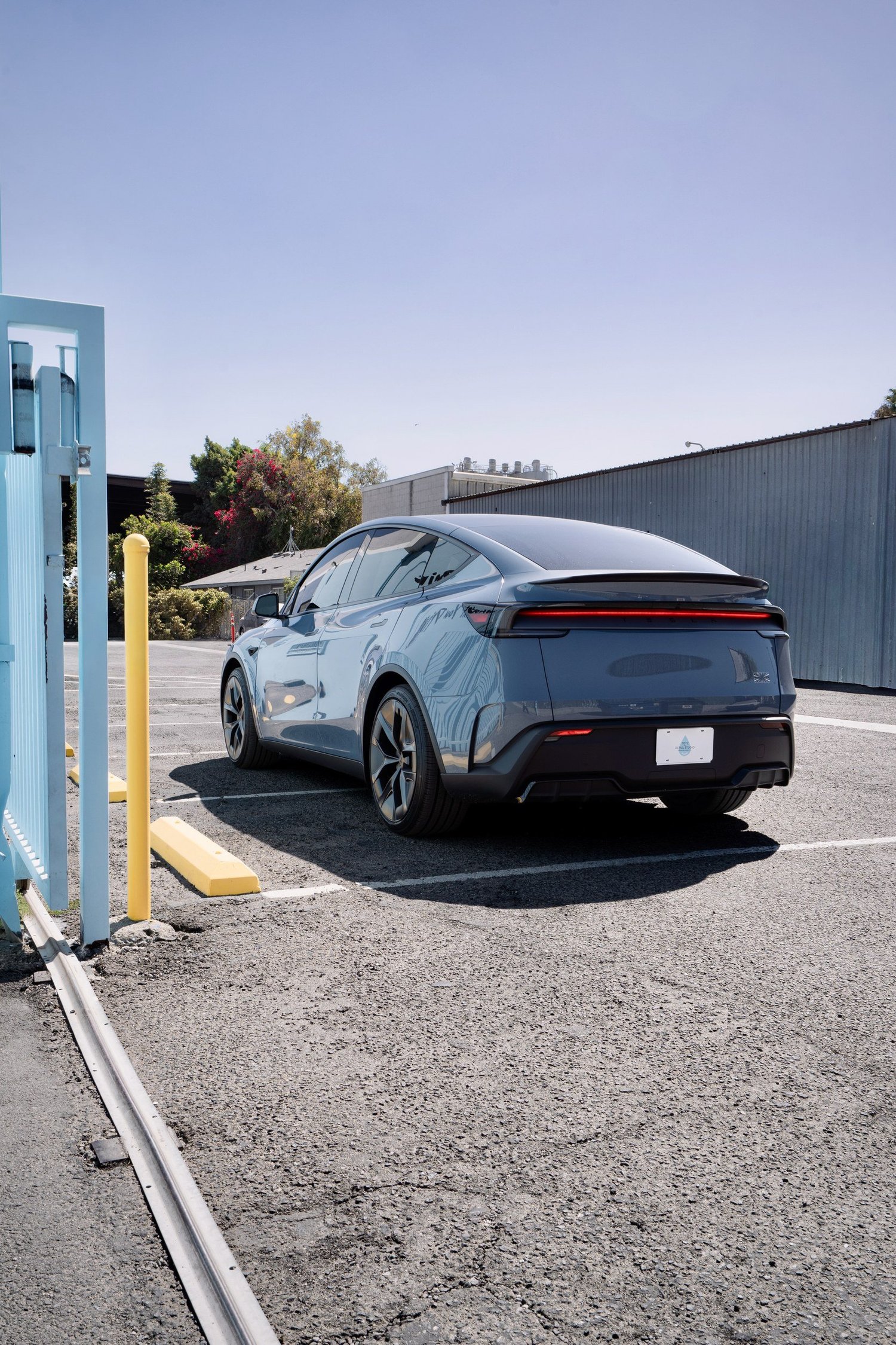 Rear three-quarter view of the Glacier Blue Model Y Performance showing its spoiler and dark rear wheel