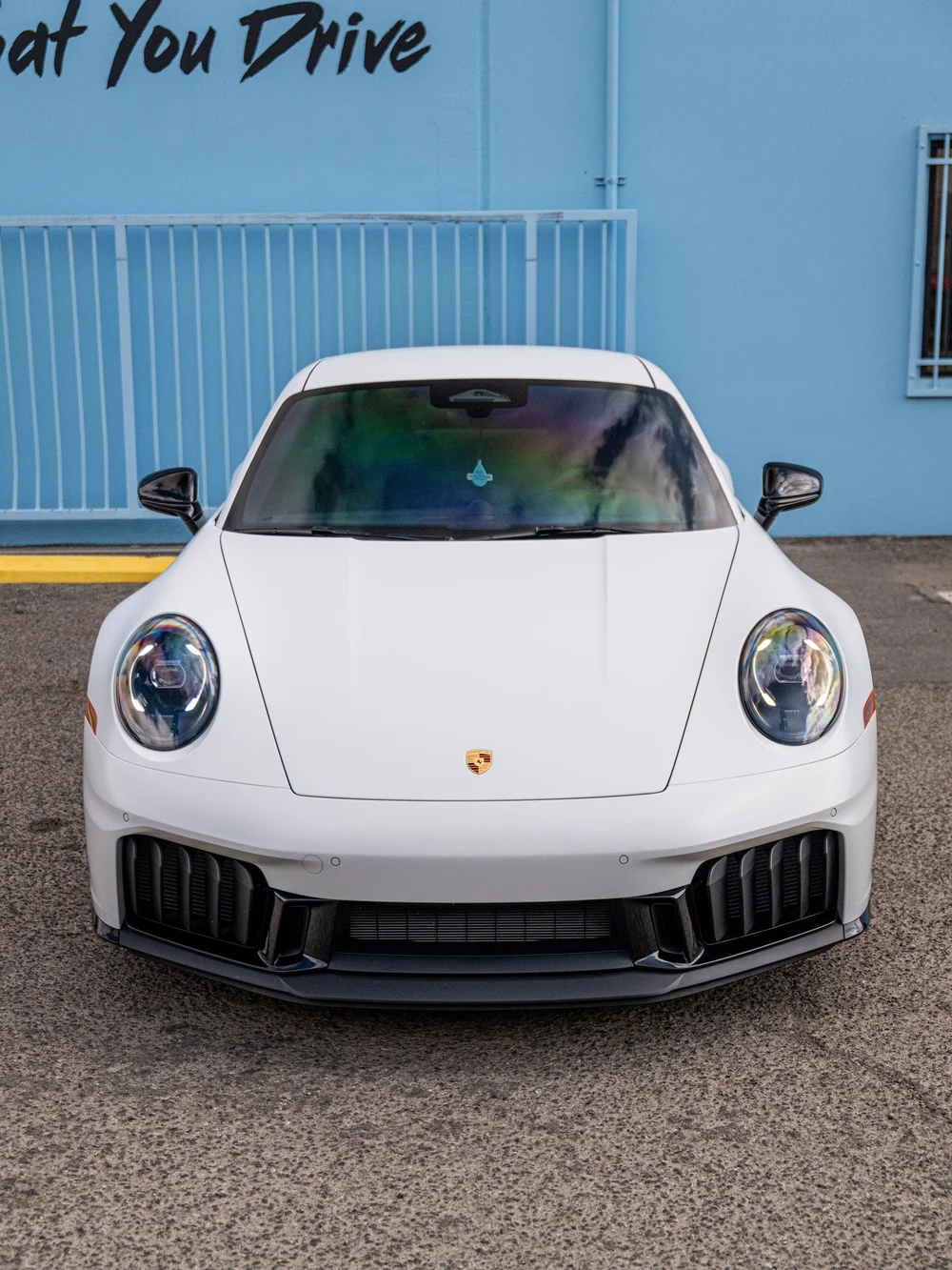 Straight front view of a 2026 Porsche 911 Carrera 4 GTS with satin-white XPEL STEALTH and gloss-black front aero trim