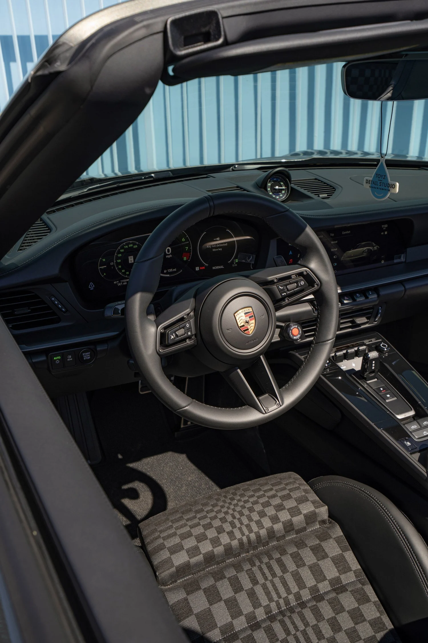 Driver's cockpit of the Porsche 911 Carrera 4S Cabriolet, showing the steering wheel, dashboard clock, center console and Pasha seat.