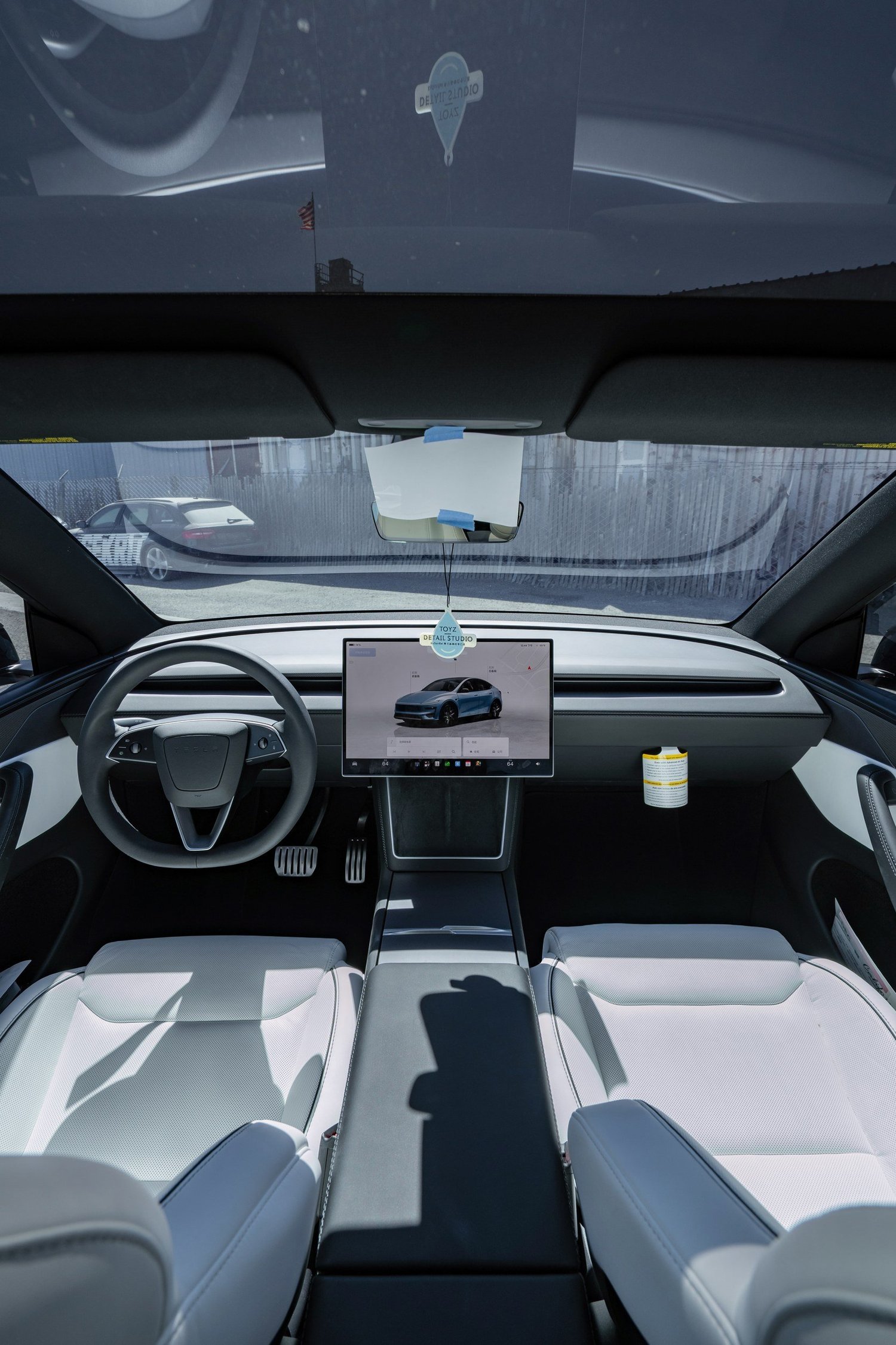 Wide cabin view of the Model Y Performance with white front seats, dashboard and panoramic glass roof