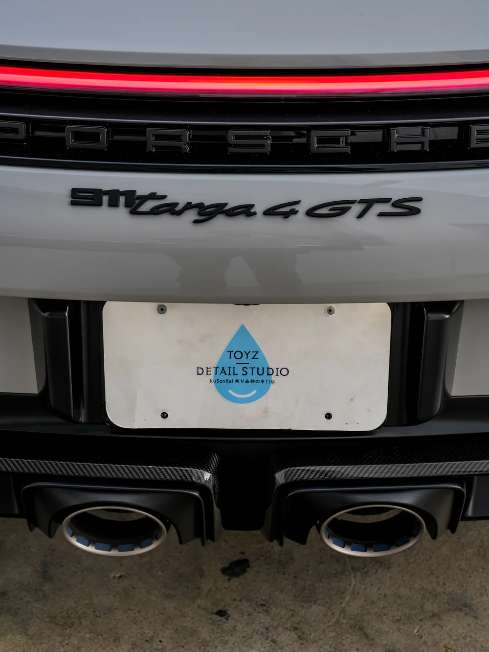 Porsche rear light bar and Targa GTS badge above the Toyz plate and twin exhaust outlets