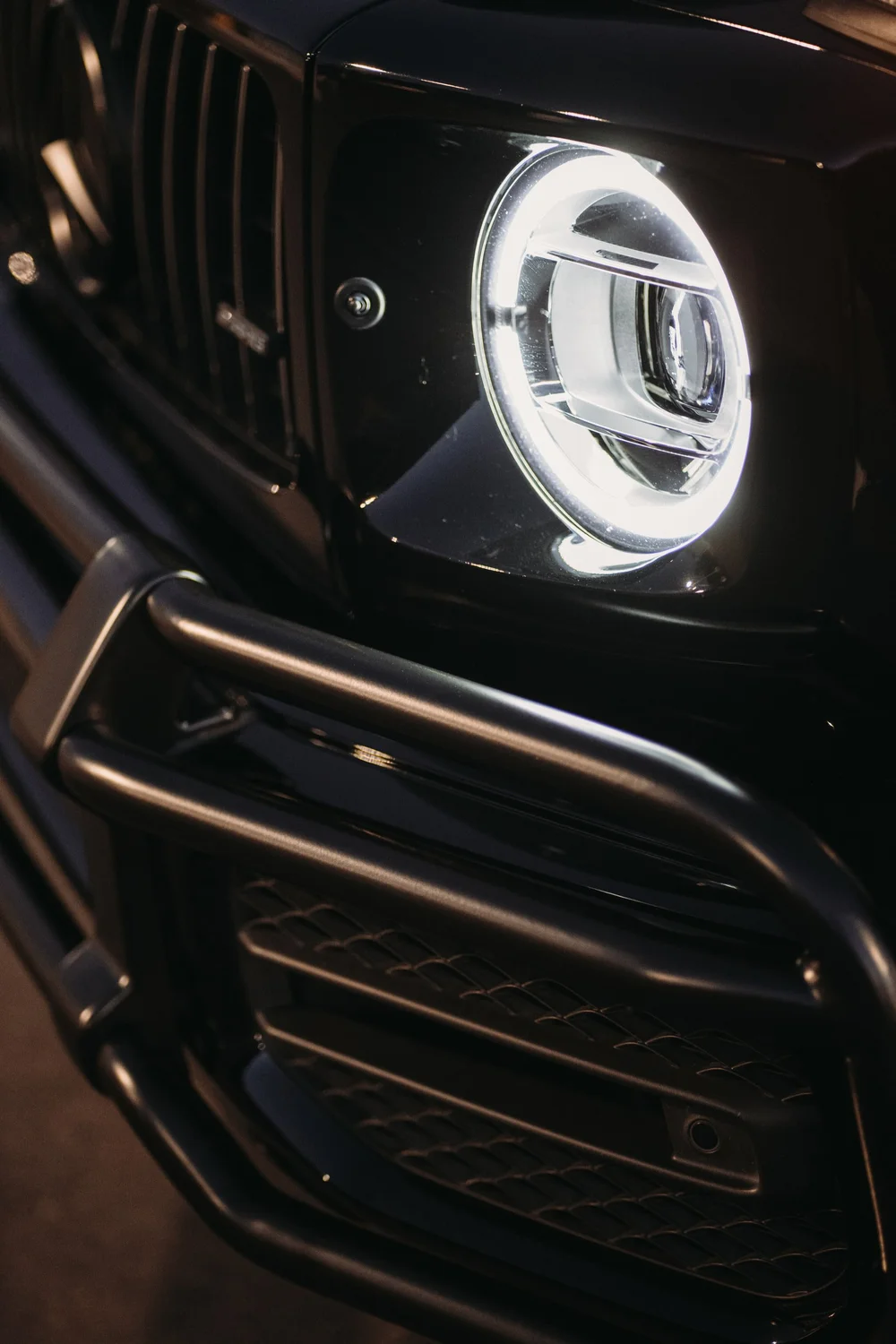 Mercedes-AMG G 63, angled close-up of the round headlight and front grille