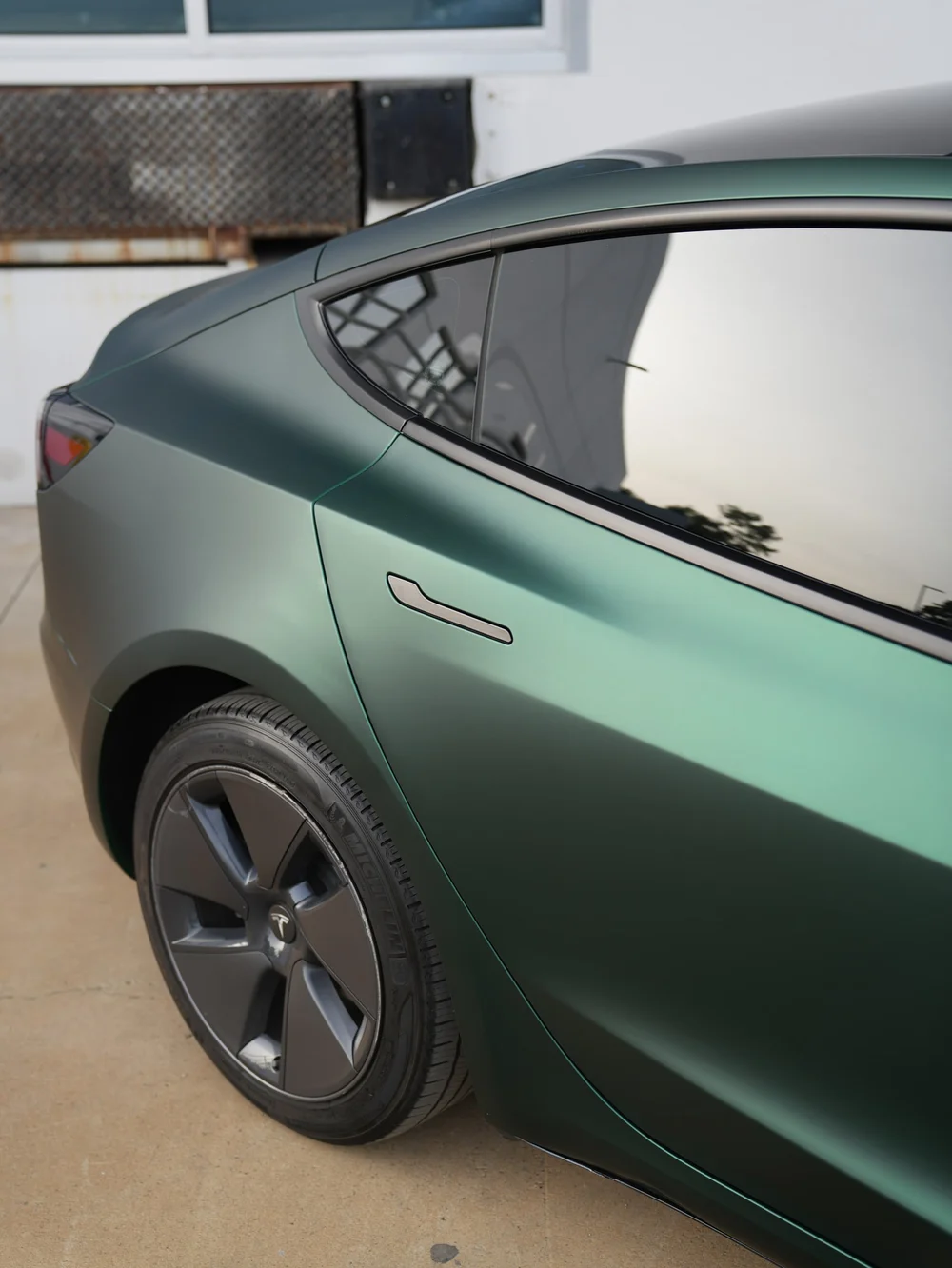 Ghost Matte Green vinyl wrap on the Tesla Model 3 rear door and quarter panel beside the flush door handle