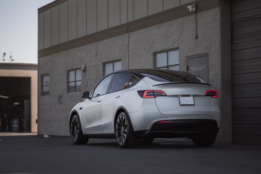 Landscape rear three-quarter view of the complete Tesla Model Y with 3M 2080 Satin Pearl White vinyl