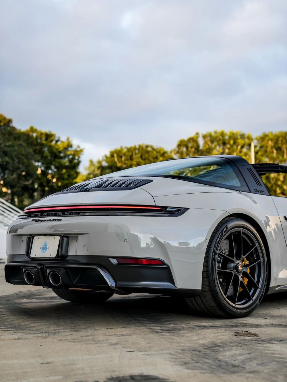 Close Porsche Targa rear corner with a dark wheel, red light bar and twin exhaust outlets