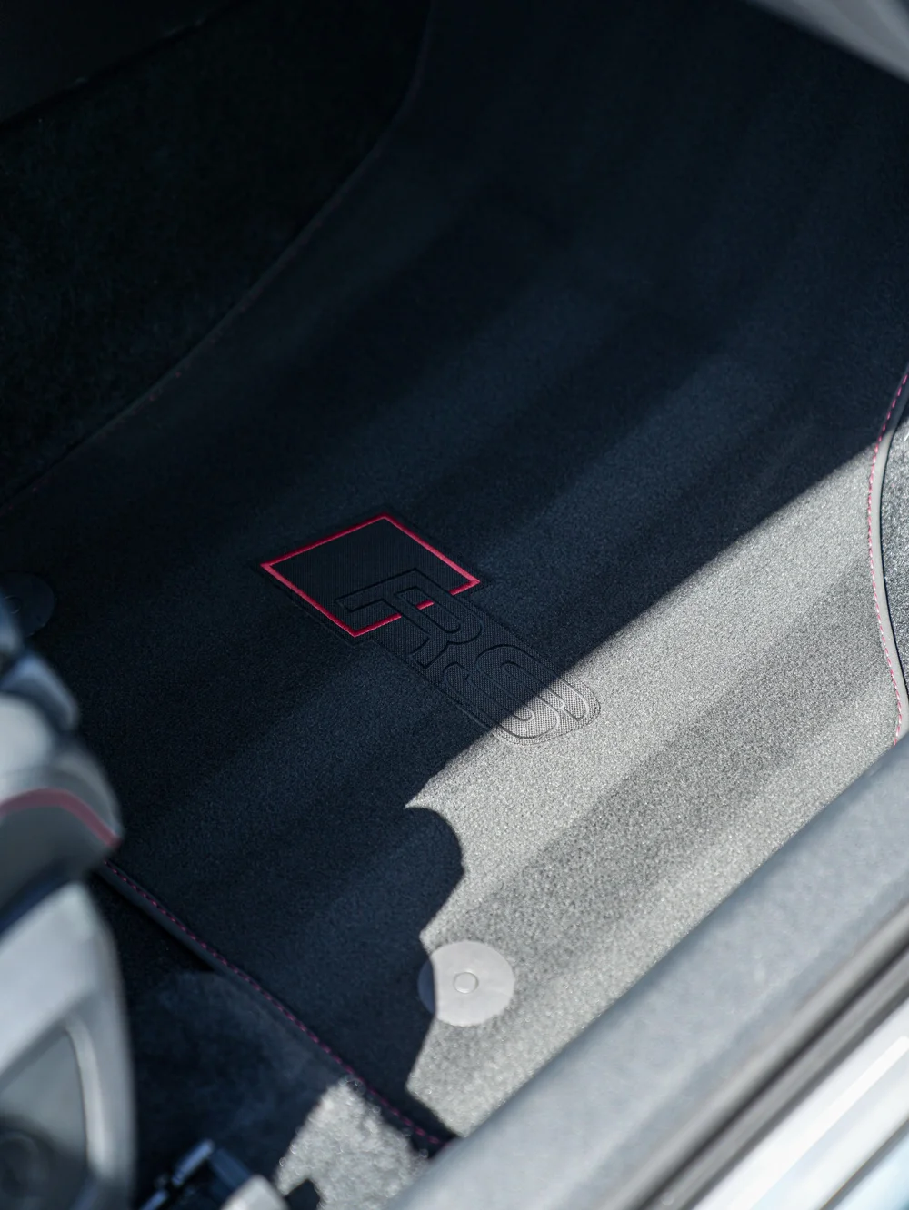 Dark Audi footwell mat with an embroidered RS emblem beside the light door sill