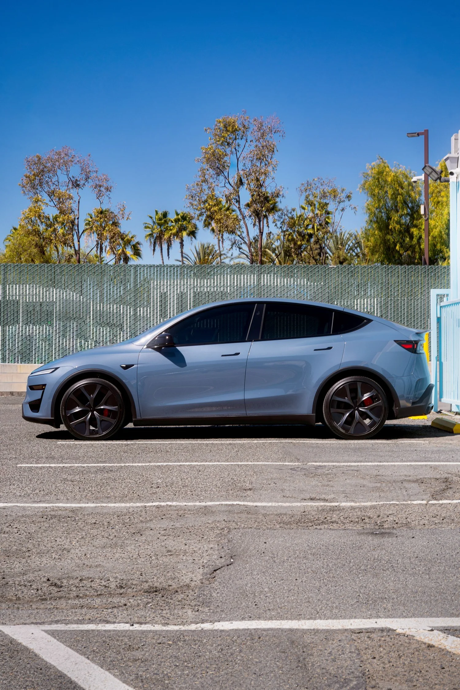 Side profile of the Glacier Blue Model Y Performance showing dark wheels and front glass matched visually to factory rear privacy glass