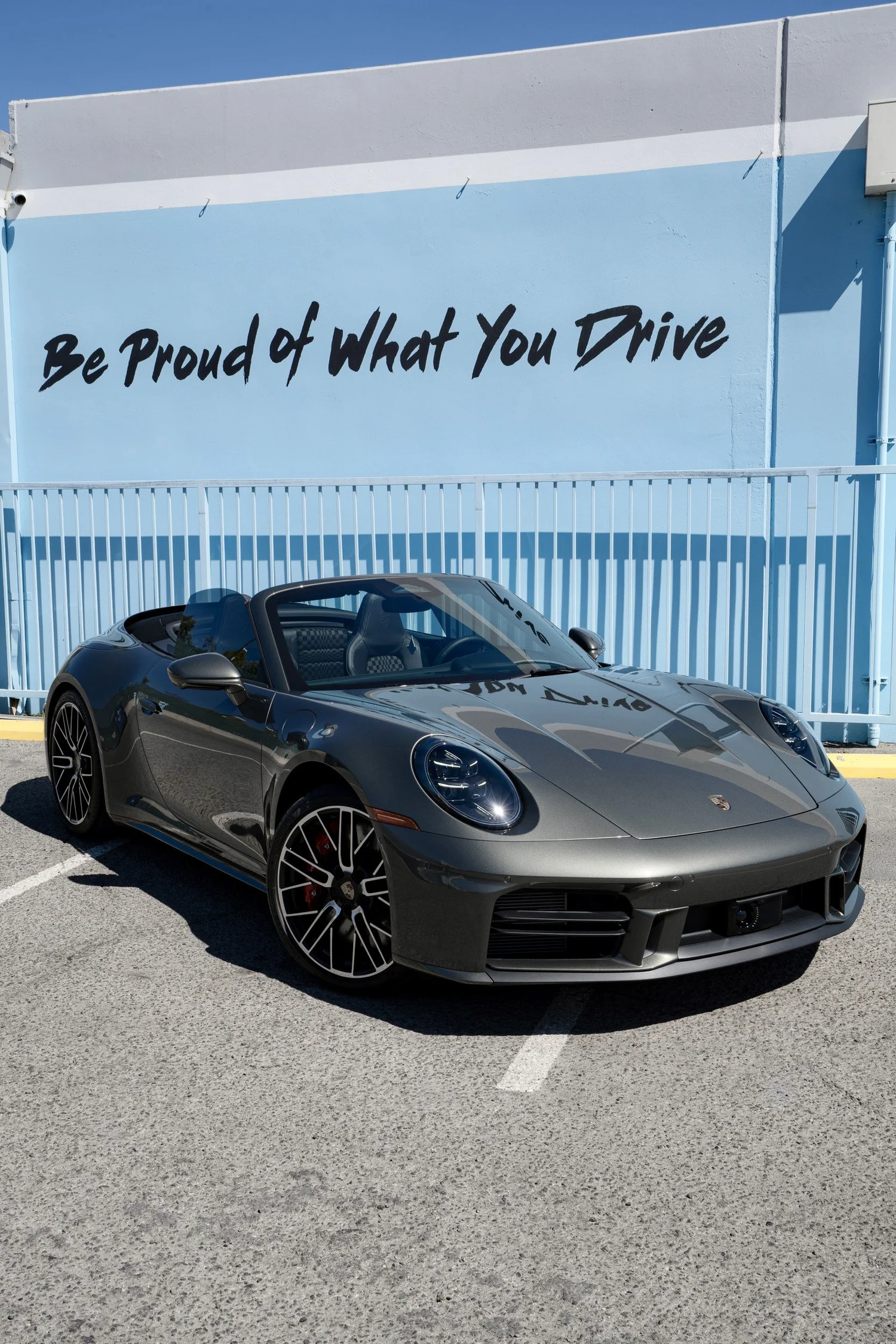 Front three-quarter view of the Vanadium Grey Metallic 2026 Porsche 911 Carrera 4S Cabriolet with the soft top lowered outside Toyz Detail Studio.