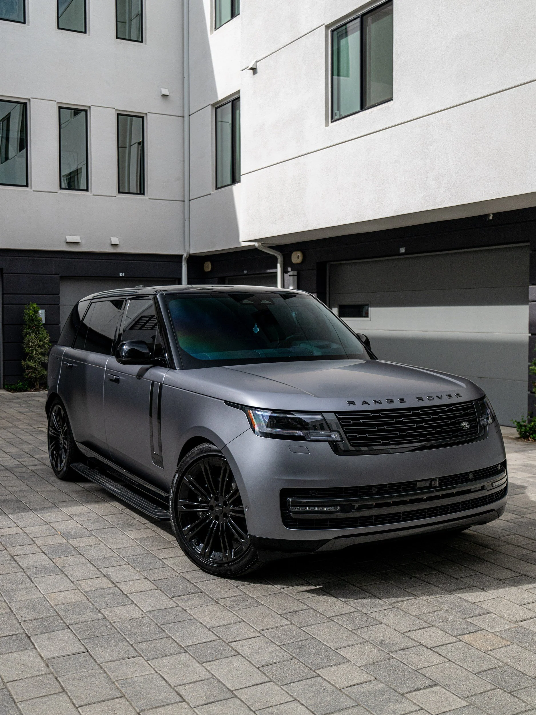 Front three-quarter view of the Eiger Grey 2026 Range Rover LWB P400 SE with satin painted panels and gloss black wheels.