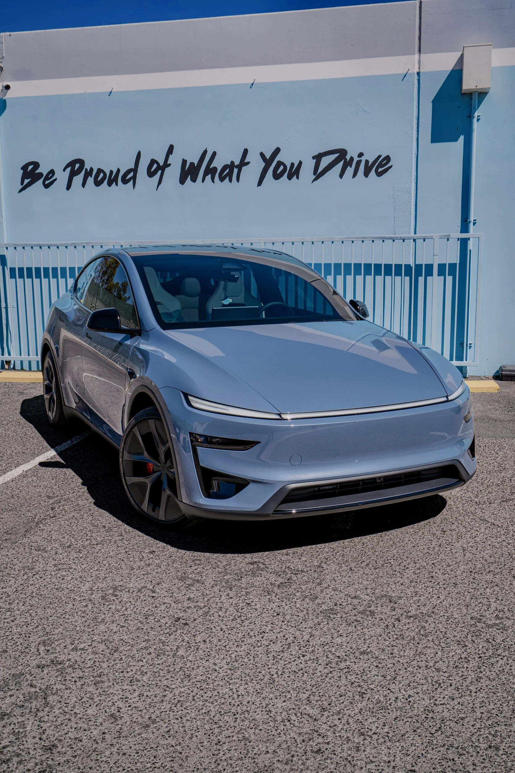 Front three-quarter view of the Glacier Blue 2026 Tesla Model Y Performance with dark wheels and factory red brake calipers