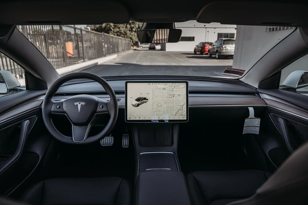 Wide view of the Tesla Model 3 front cabin with steering wheel, central screen and center console
