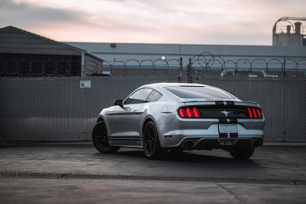 Wide rear three-quarter view of the Ford Mustang with racing stripes across the rear deck and bumper