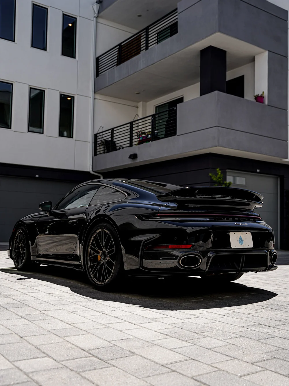 Low rear three-quarter view of the Jet Black Metallic Turbo S with both wheels, rear wing and diffuser visible.