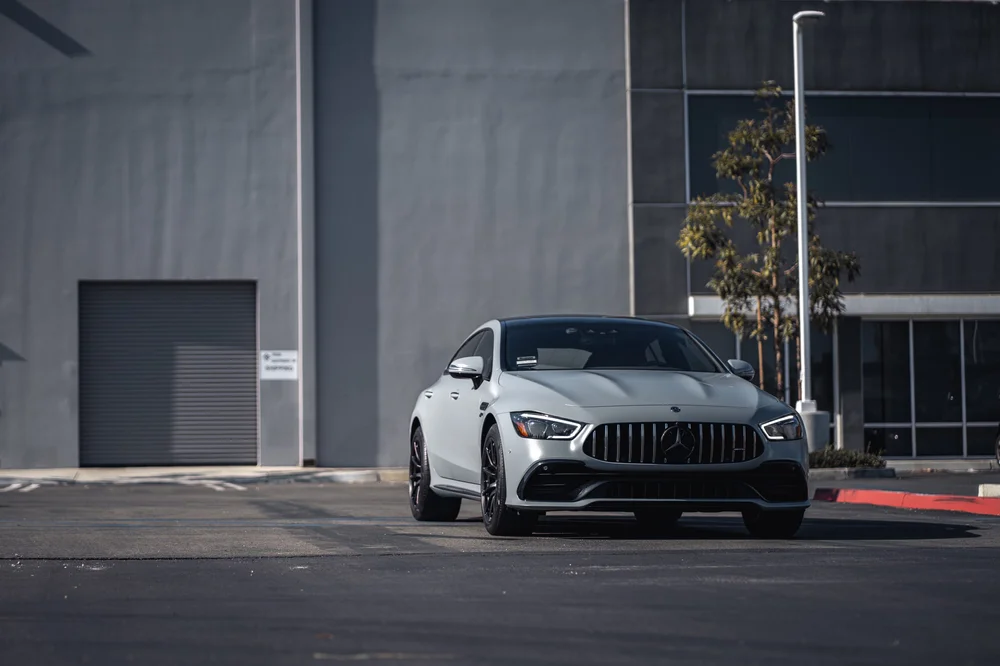 Wide front view of the Mercedes-AMG GT 53 showing the Battleship Grey hood, grille and front wheels