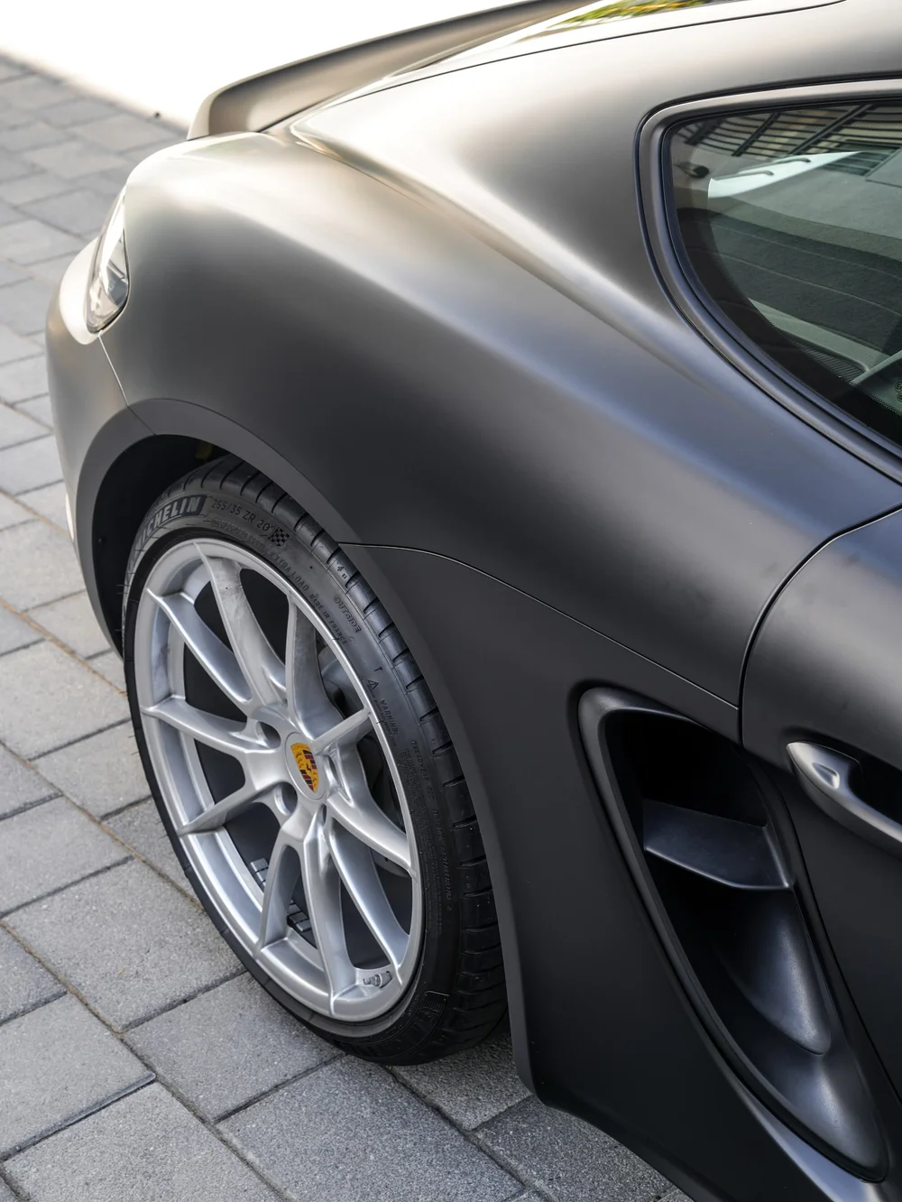 Porsche 718 Cayman GTS with 3M Satin Black vinyl wrap, rear wheel, quarter panel and side air-inlet detail