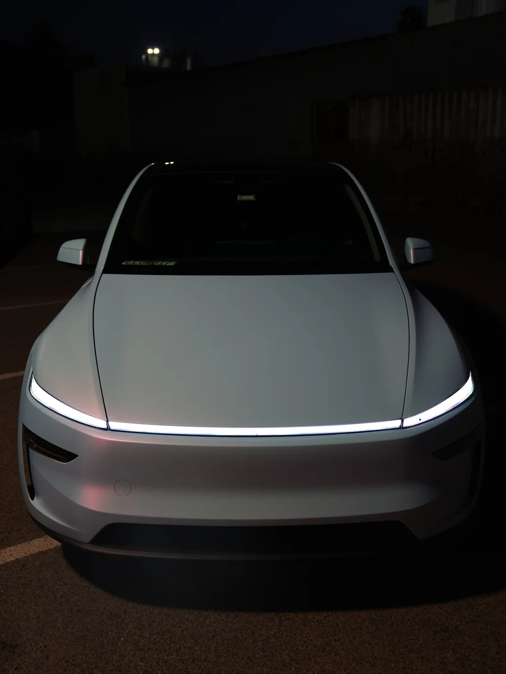 Elevated direct front view of a Tesla Model Y with white-to-blue vinyl after dark