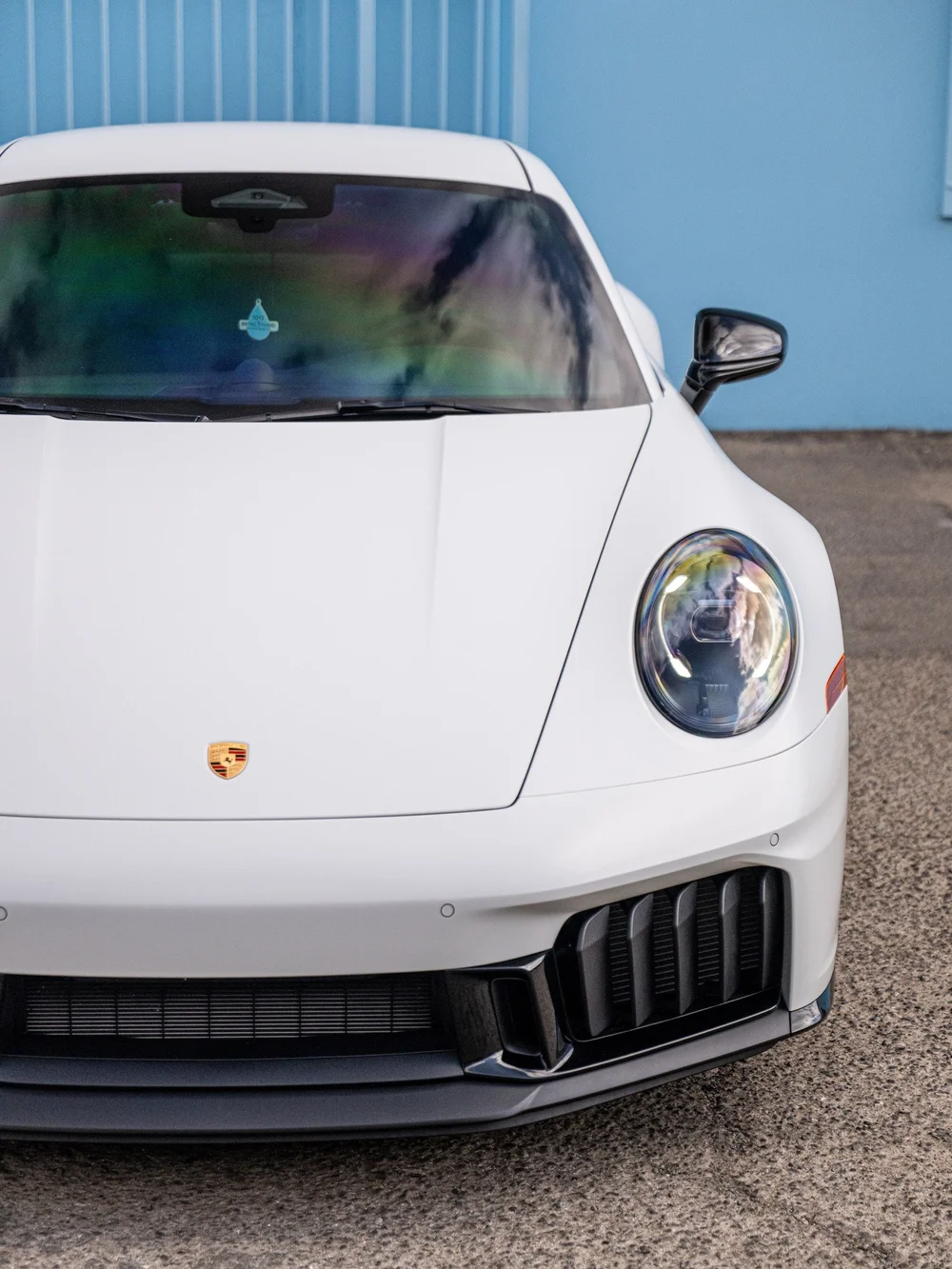Close front view of a Porsche 992.2 Carrera 4 GTS showing the satin-white hood, headlight and gloss-black front bumper details