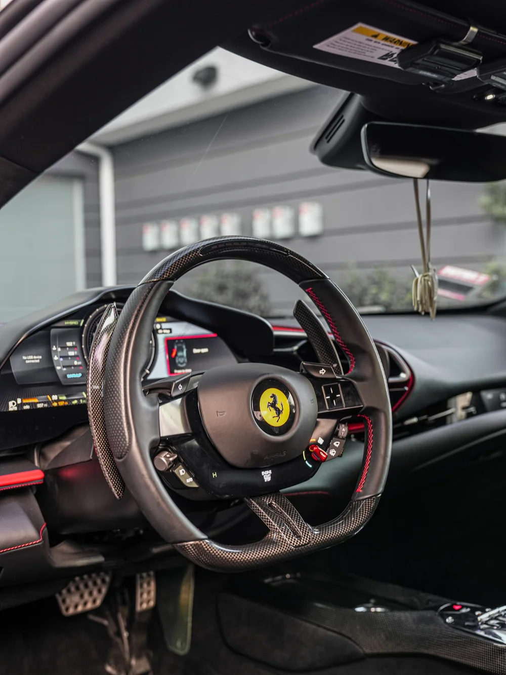 Ferrari cockpit with a prancing-horse steering wheel, dark dashboard and visible windshield