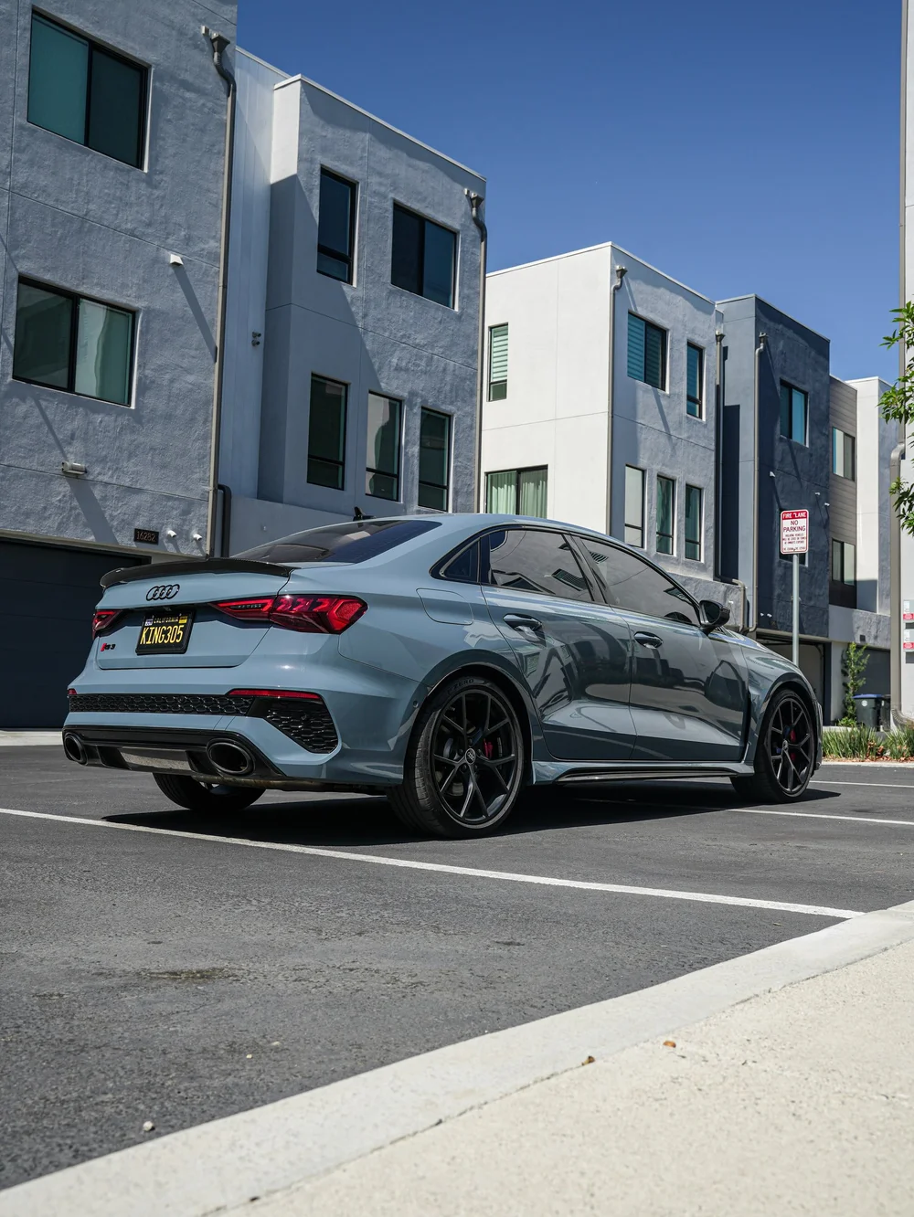 Complete Audi RS 3 from a low rear three-quarter angle beside modern buildings