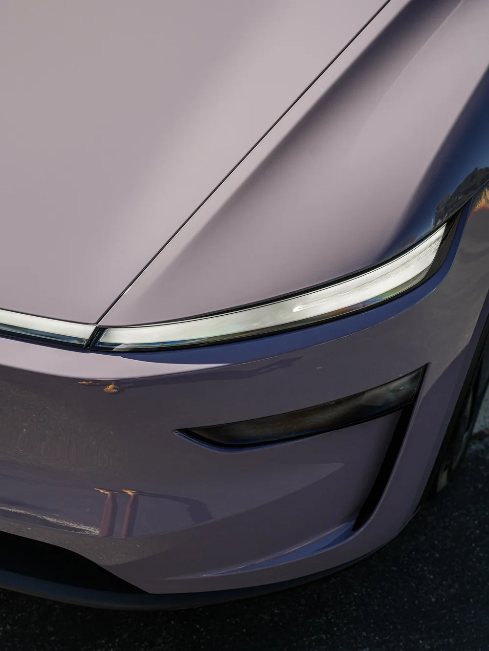 Tesla Model Y with Provence Violet vinyl wrap, close view of the front light and Provence Violet hood edge
