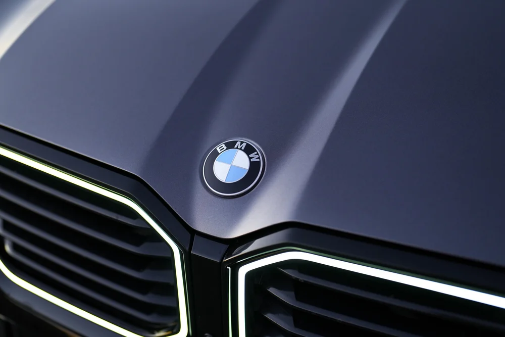 Close hood detail showing the BMW emblem between raised grey contours above the illuminated grille borders.