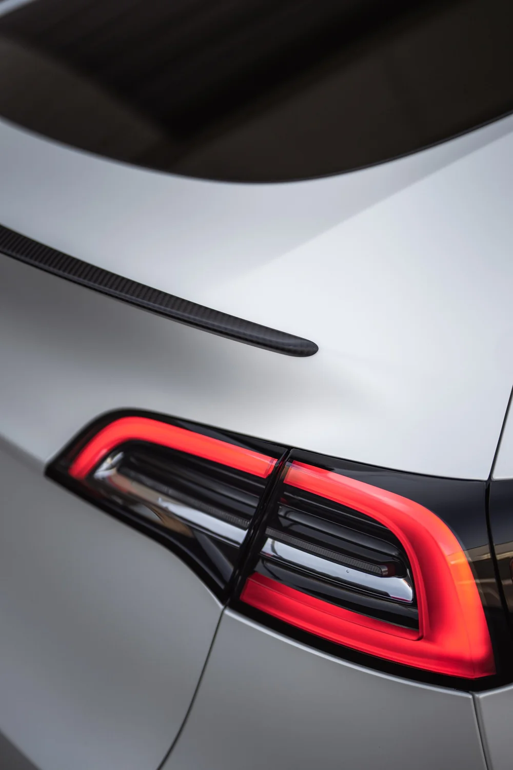 Rear hatch and illuminated taillight detail on the Tesla Model Y with 3M 2080 Satin Pearl White vinyl