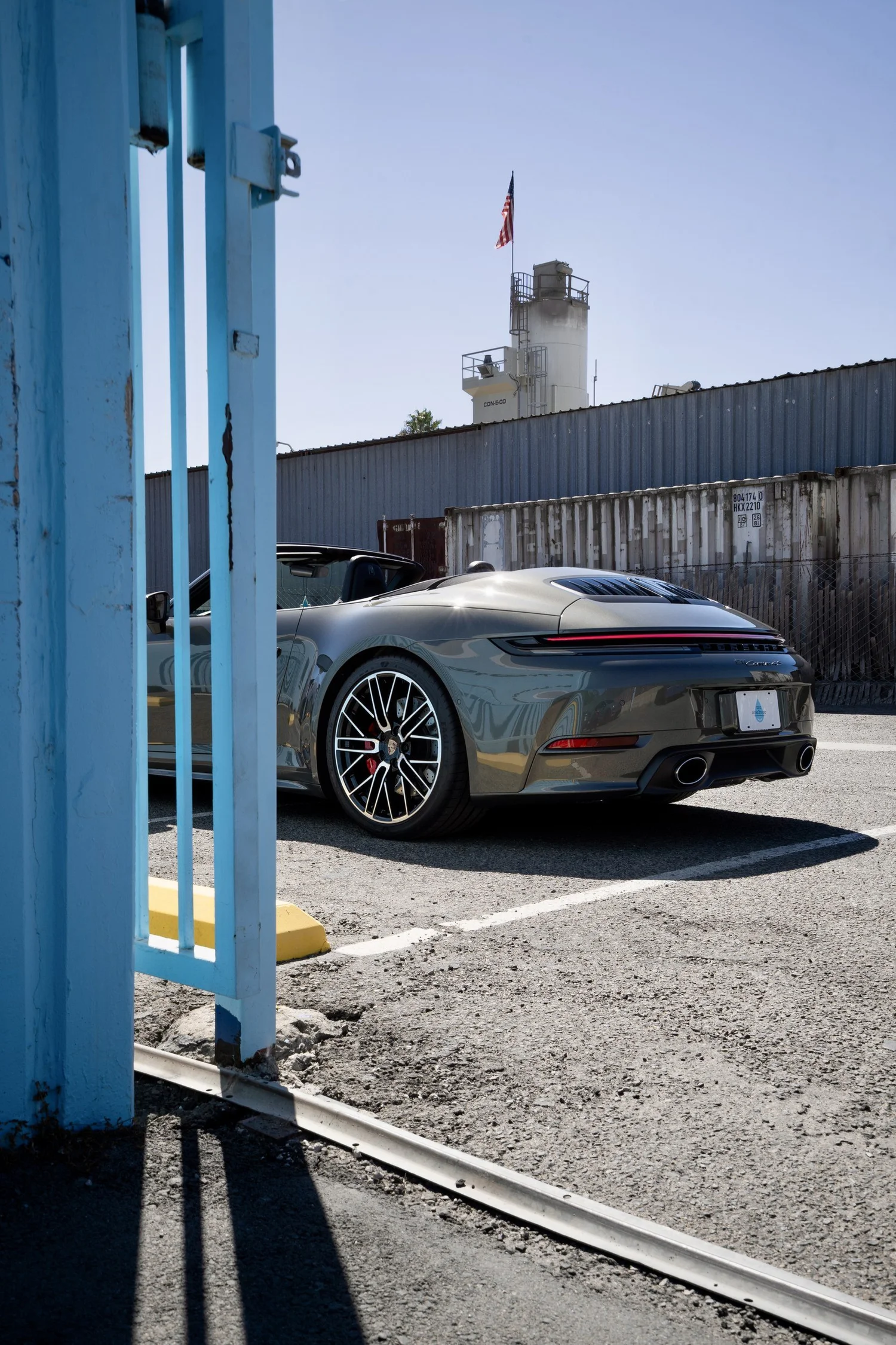 Rear quarter and wheel of the Vanadium Grey Porsche Cabriolet viewed through the blue Toyz entrance structure.