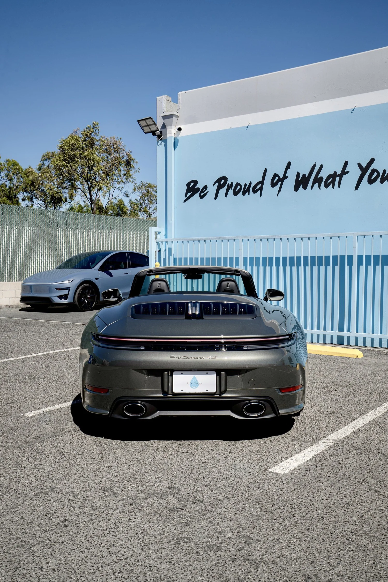 Straight-on rear view of the Porsche 911 Carrera 4S Cabriolet with the roof lowered, twin exhaust outlets and rear light bar visible.