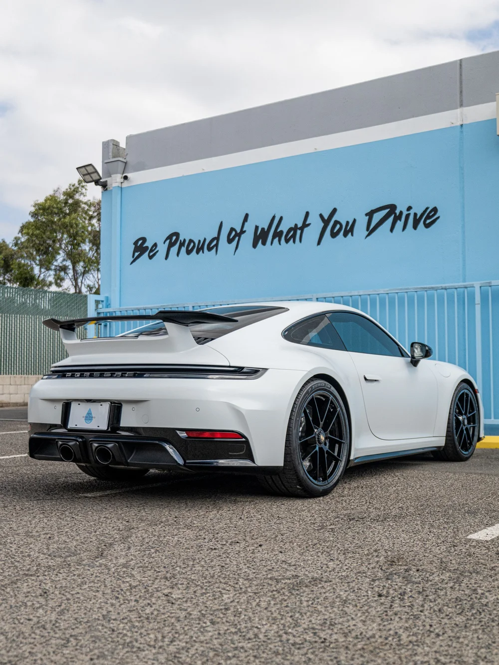 Rear three-quarter view of a 2026 Porsche 911 Carrera 4 GTS with satin-white XPEL STEALTH and gloss-black rear wing