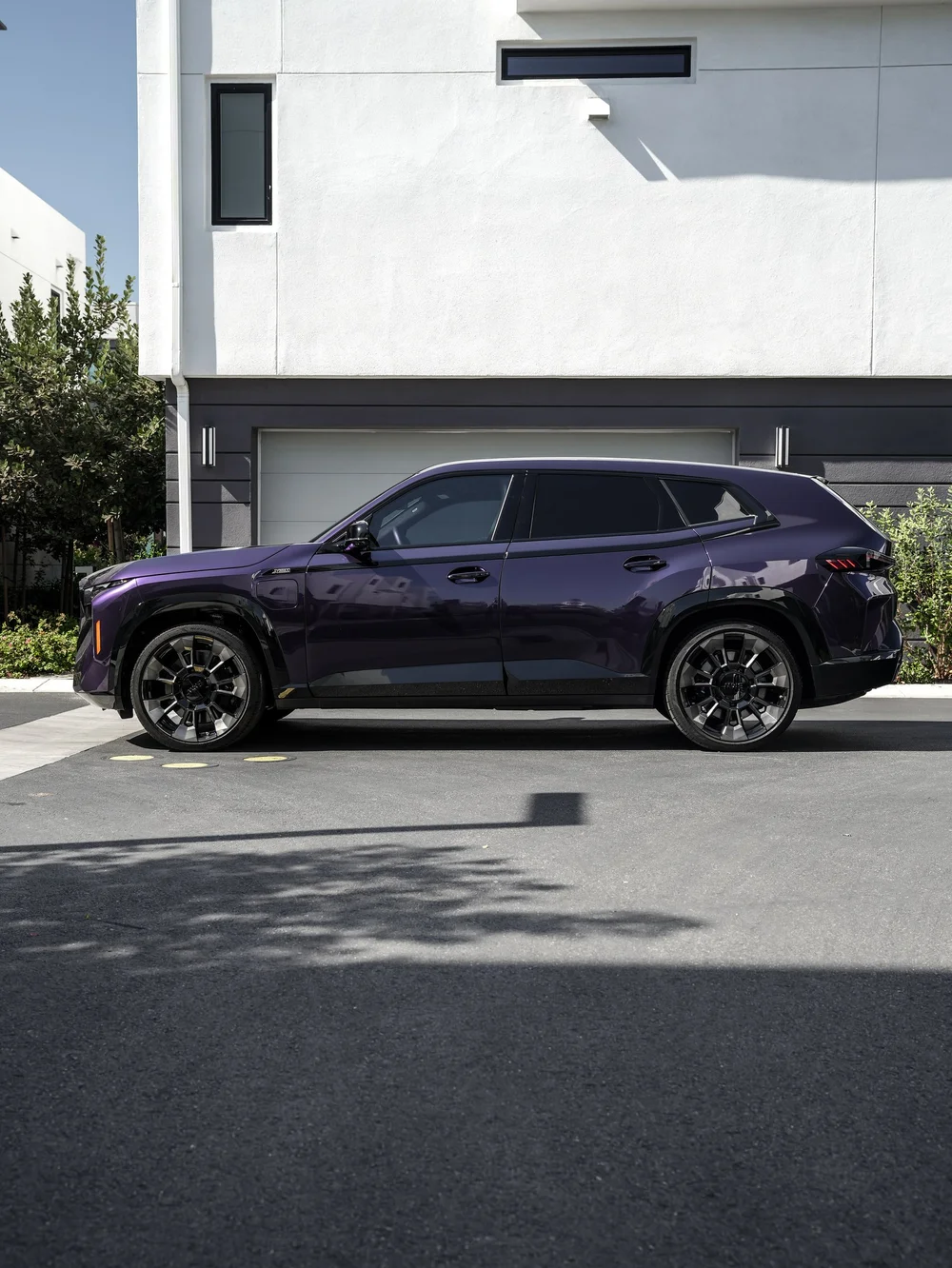 Side profile of the BMW XM with Venetian Mauve colored PPF outside a light building