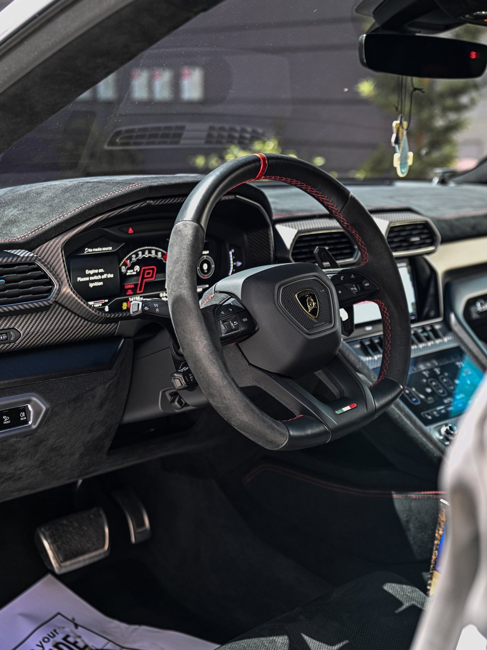 Lamborghini Urus cockpit with a dark steering wheel, instrument cluster and center screens