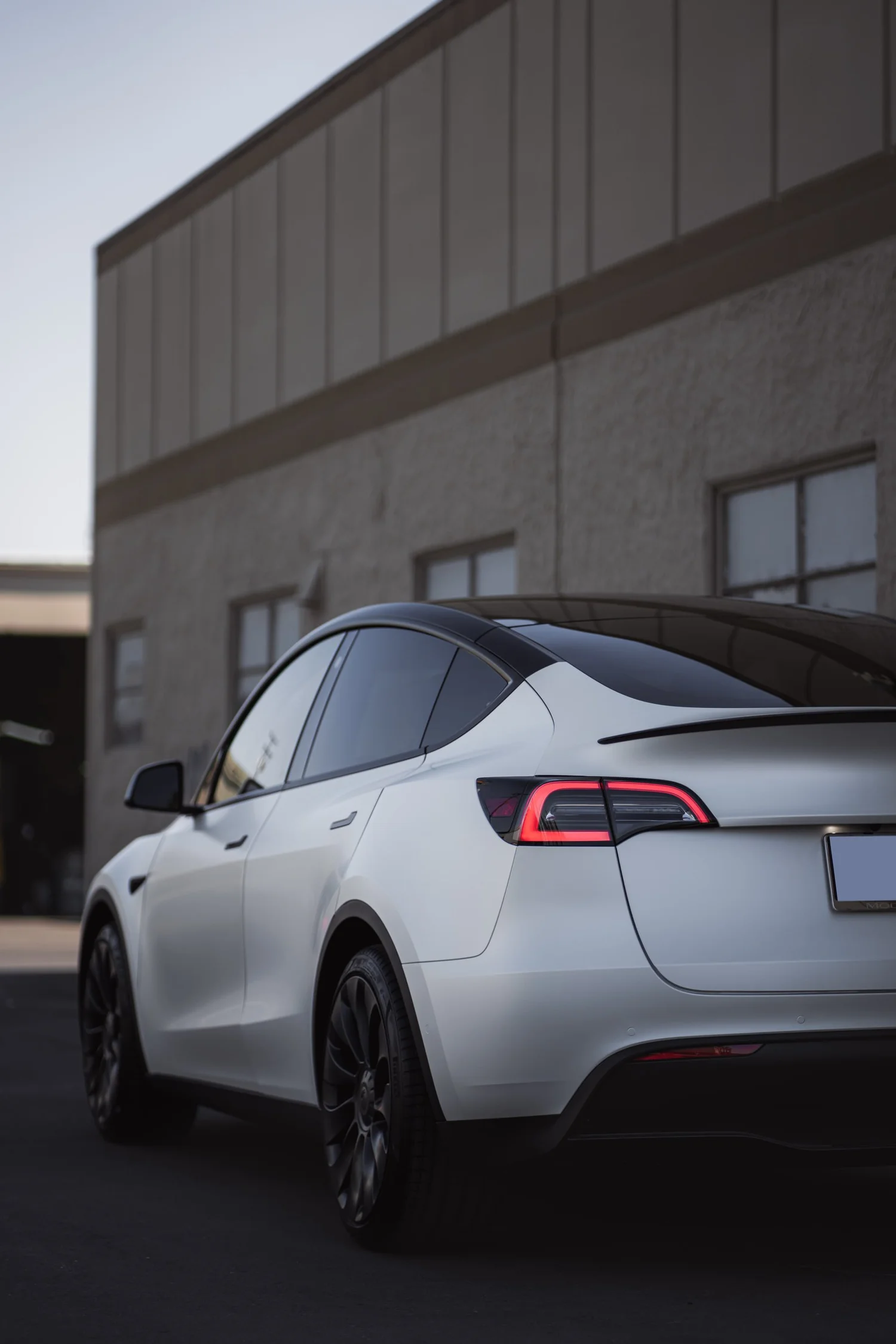 Satin Pearl White Tesla Model Y after Vinyl Wrap, low-angle rear view