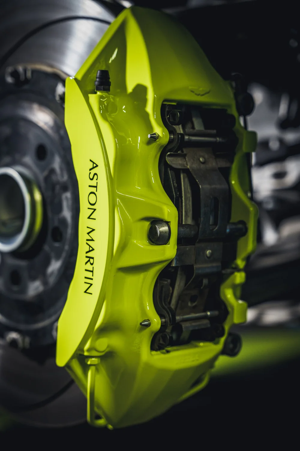 Close portrait view of the Acid Green brake caliper with Aston Martin lettering beside the brake disc