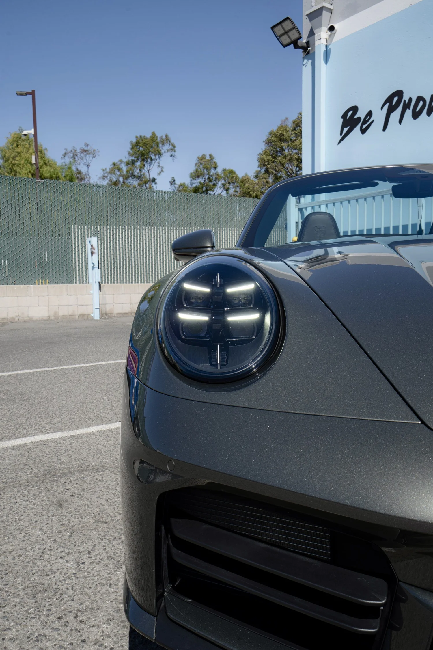 Close-up of the Porsche Cabriolet's illuminated front headlight and Vanadium Grey front bumper.