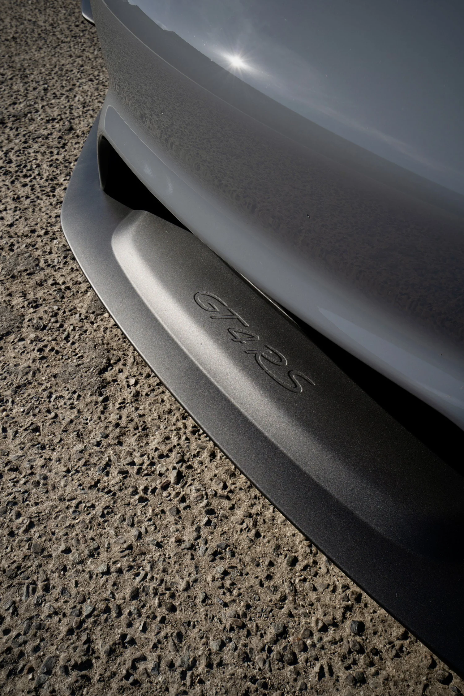 GT4 RS lettering embossed in the dark front splitter below the Arctic Grey bumper.