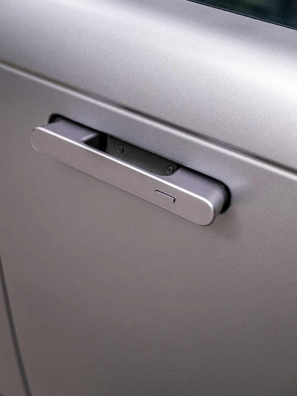 Close-up of the Range Rover flush door handle, showing its sculpted shape and the surrounding satin Eiger Grey surface.