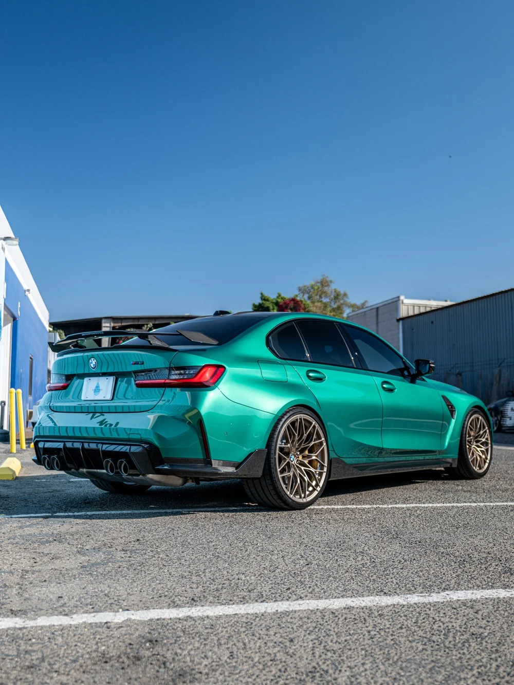 Rear three-quarter view of the Isle of Man Green 2025 BMW M3 with M Performance rear wing and carbon lower aero