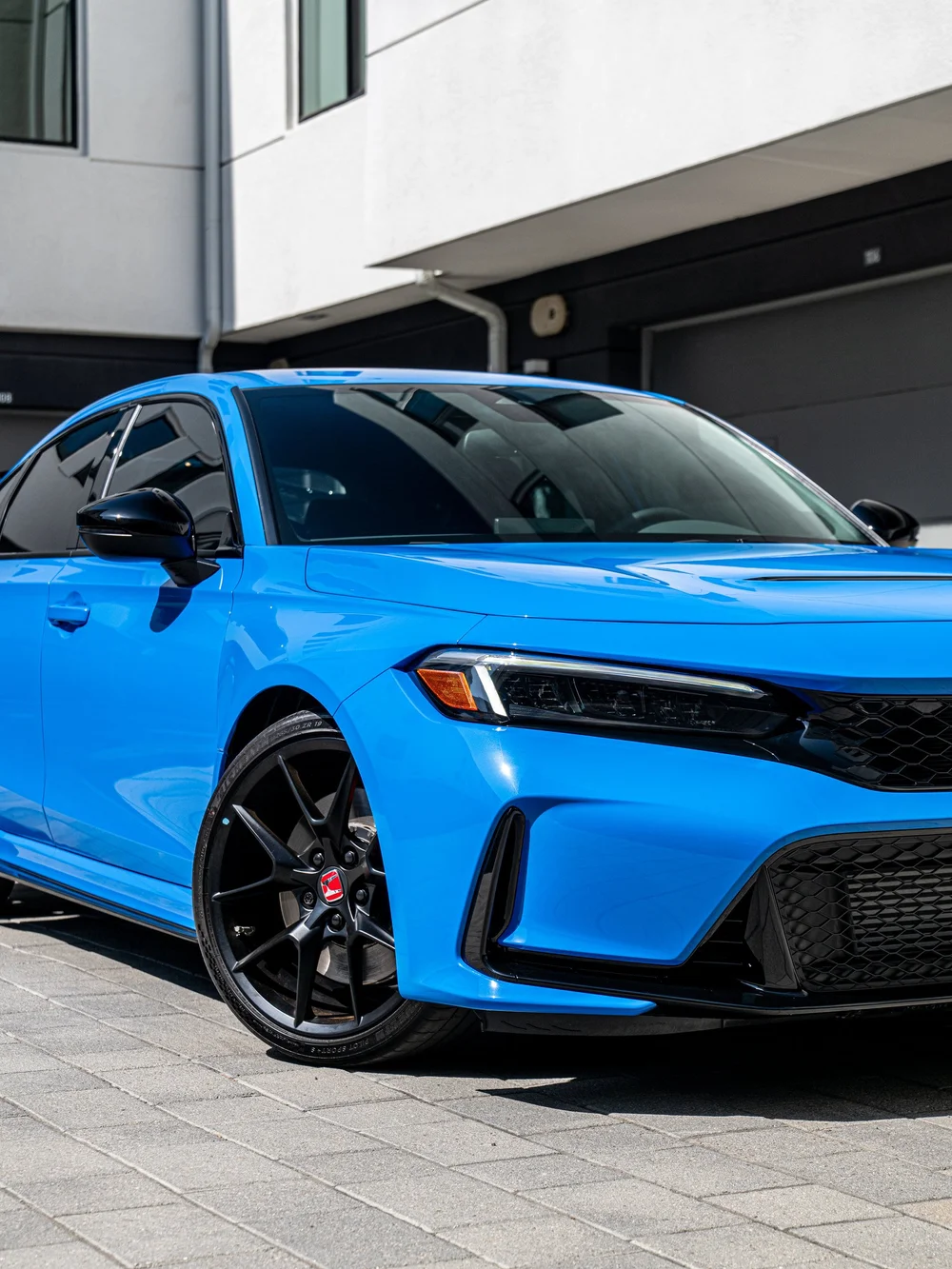 Front corner of a Boost Blue Pearl 2026 Honda Civic Type R showing the protected hood, bumper and fender