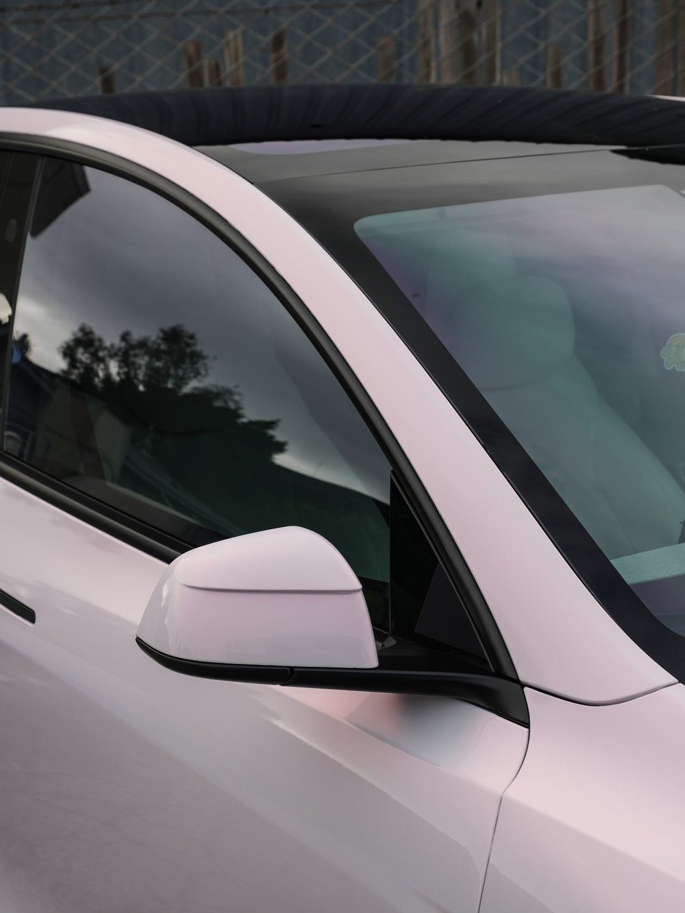Mirror, front-door and windshield-edge detail on a Tesla Model Y with Pale Blush Pink vinyl