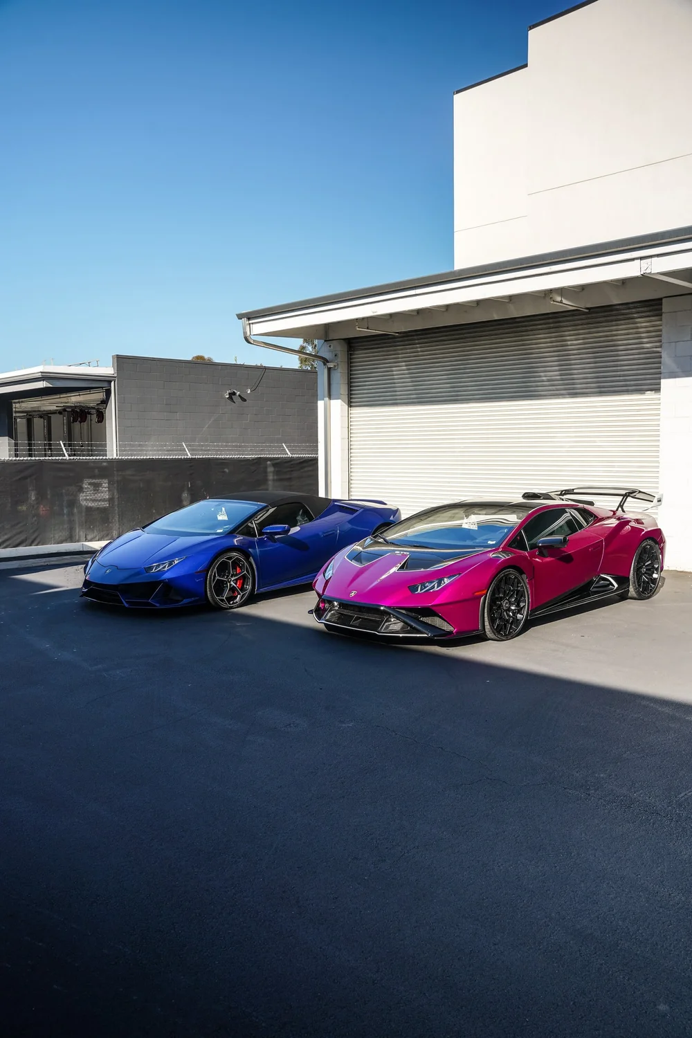Blue and pink Lamborghinis parked together in a front three-quarter composition