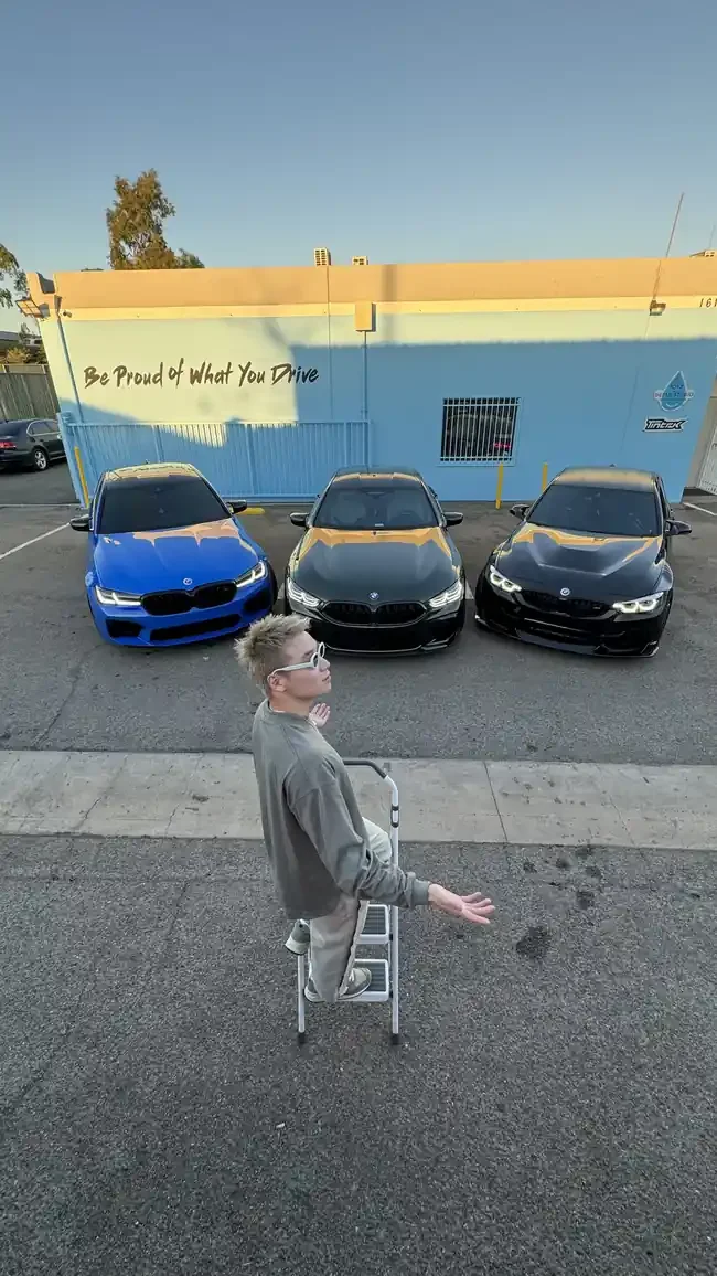 Max outside Toyz Detail Studio with three BMW vehicles