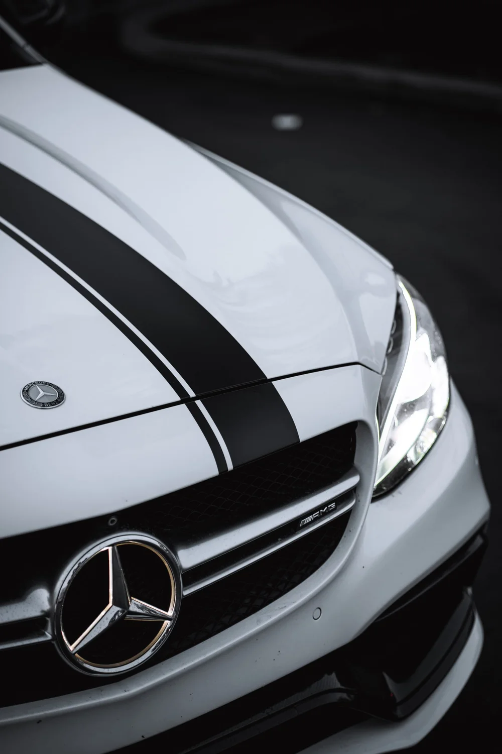 Mercedes-Benz C 63 hood detail showing paired racing stripes above the grille and Mercedes emblem