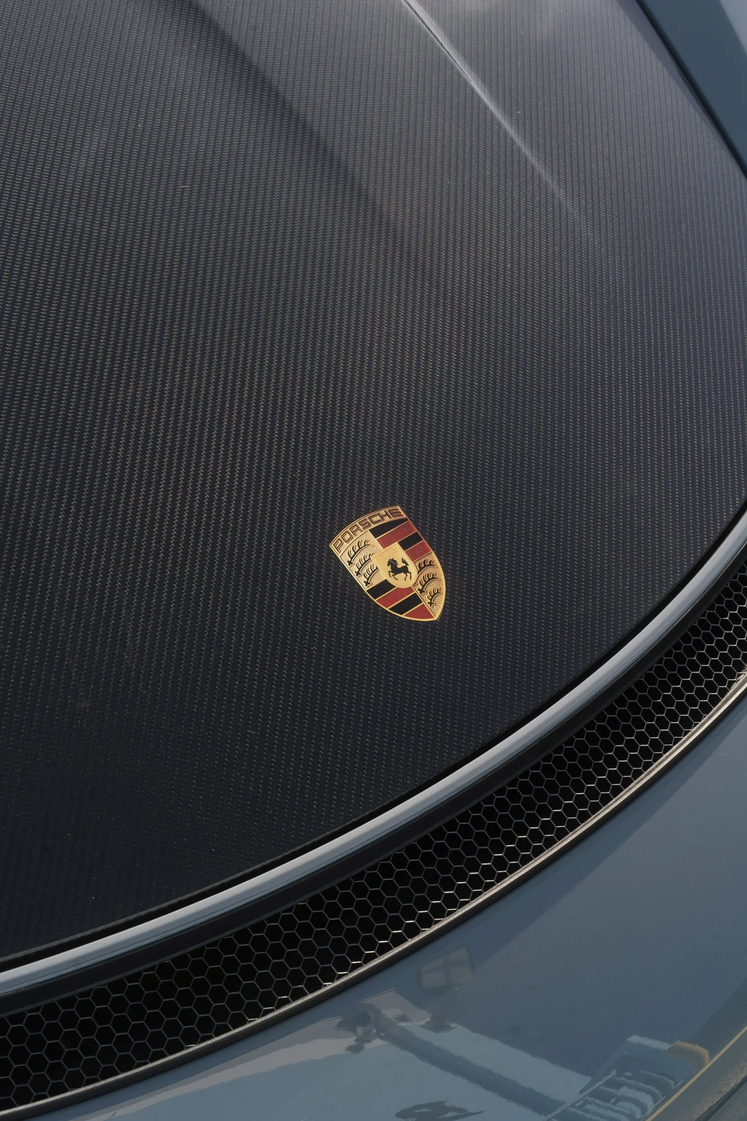Porsche crest on the GT4 RS exposed carbon hood, with the carbon weave and front grille visible.