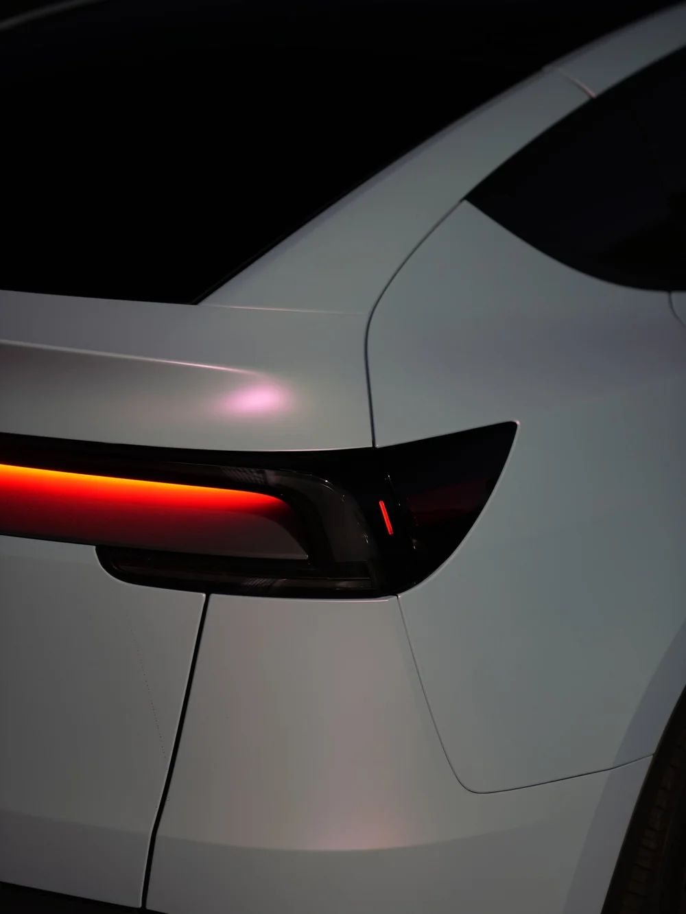 Rear fender and taillight detail of a Tesla Model Y with white-to-blue color-shifting vinyl