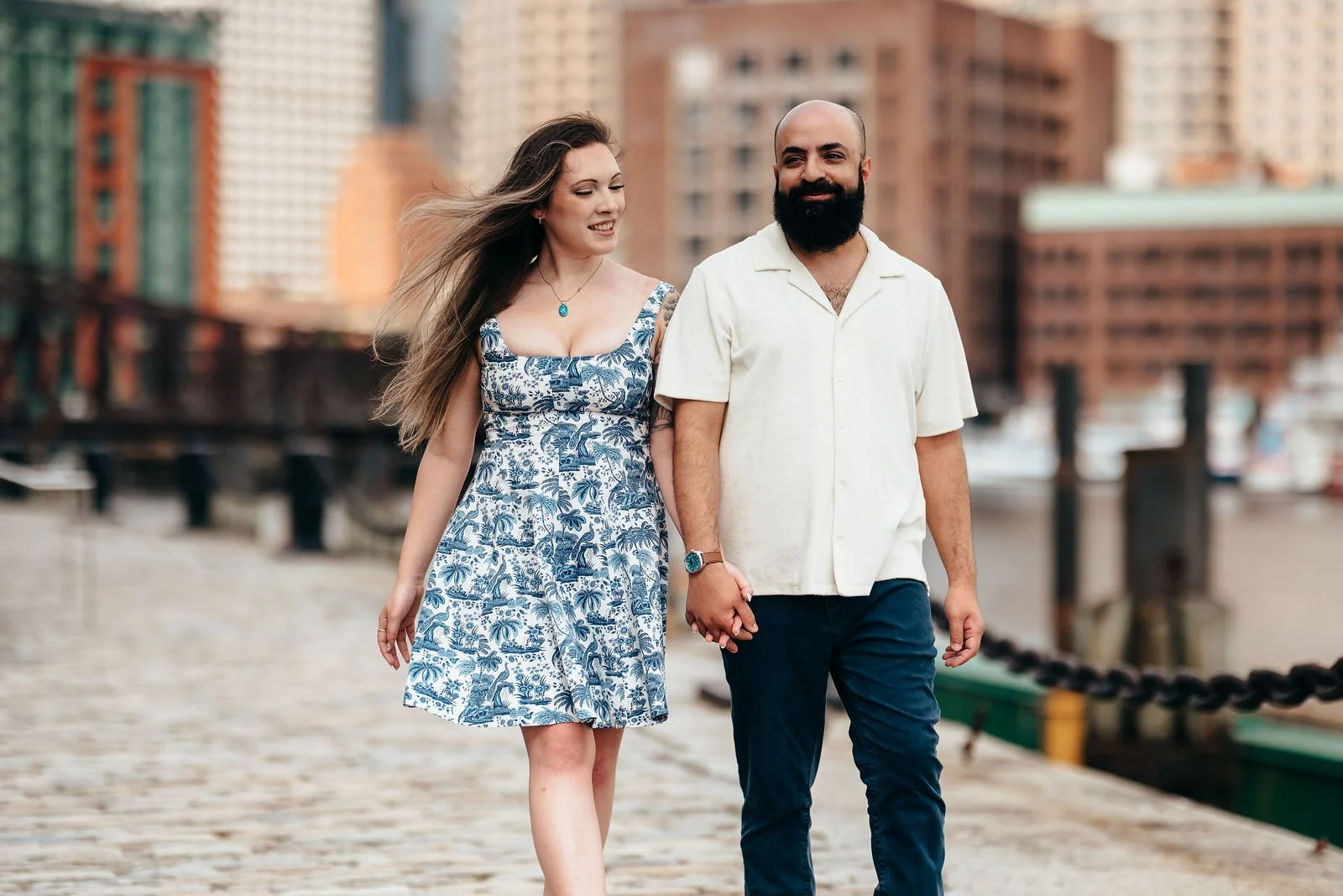 Couple walking the cobblestone streets of Boston's Seaport at their engagement session