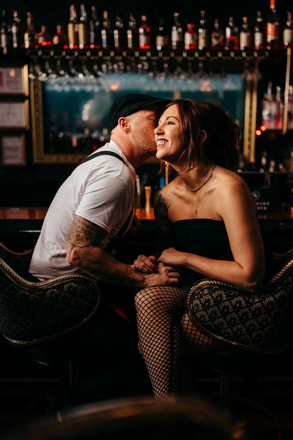 Kristin and Mike seated in ornate chairs sharing a kiss at The Candy Bar in Laconia