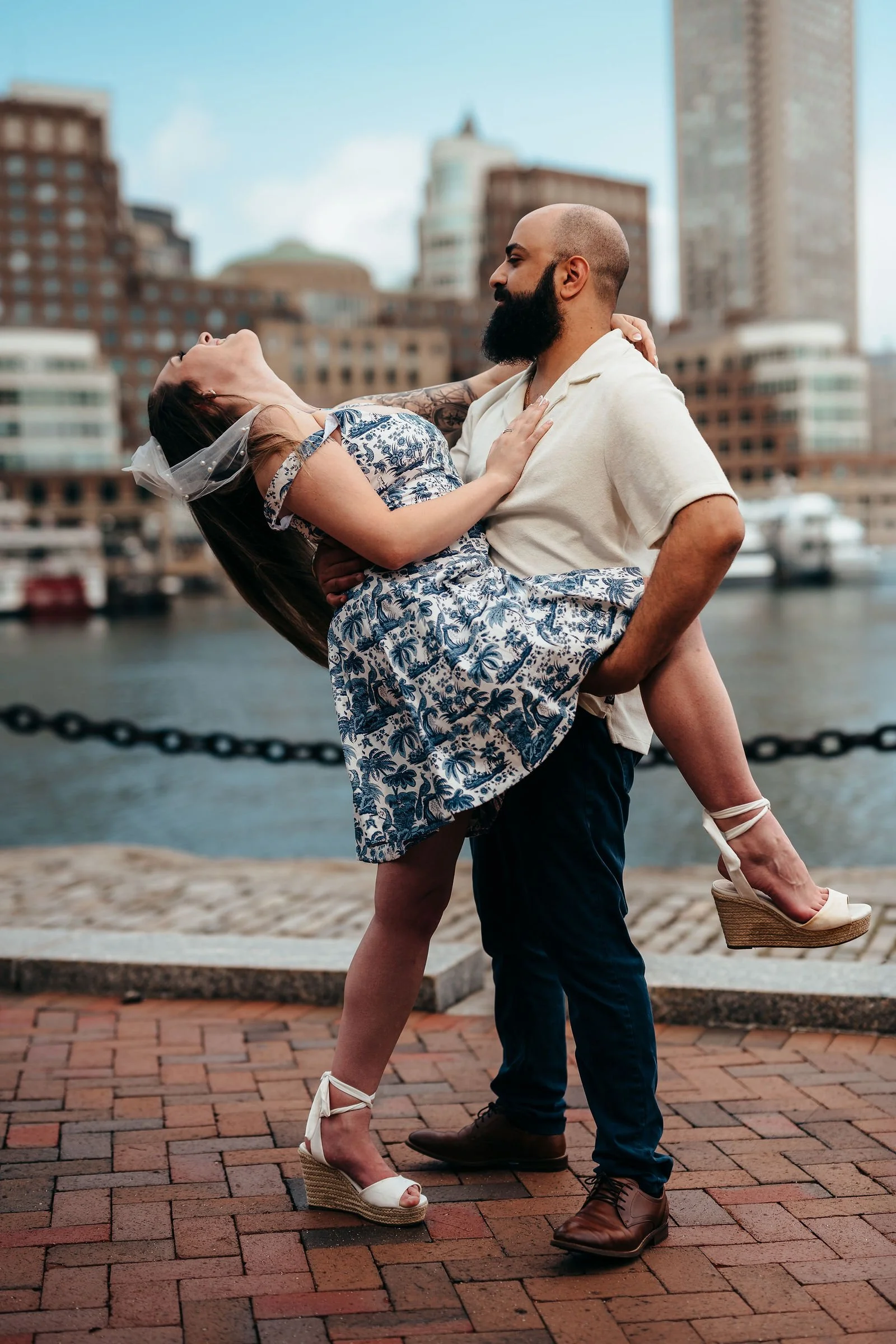 Aziz dipping Katherine for a kiss on a brick plaza in Boston's Seaport