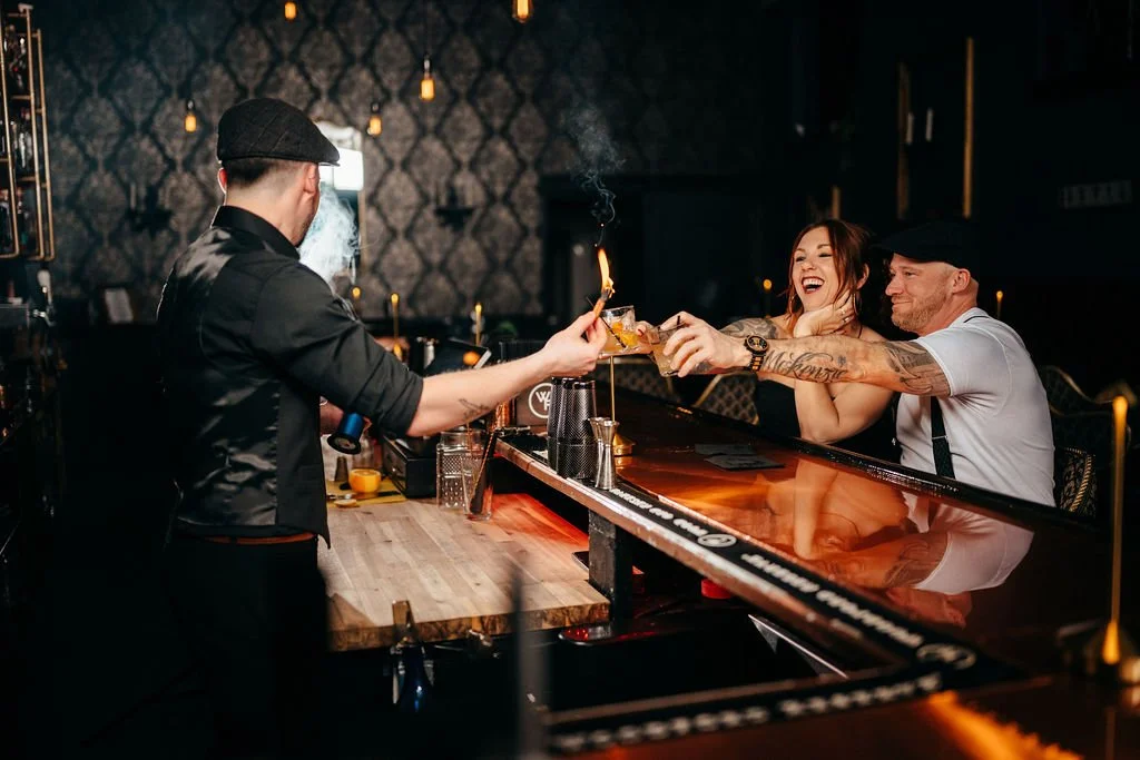 Bartender lighting a flaming cocktail for Kristin and Mike at their speakeasy engagement session